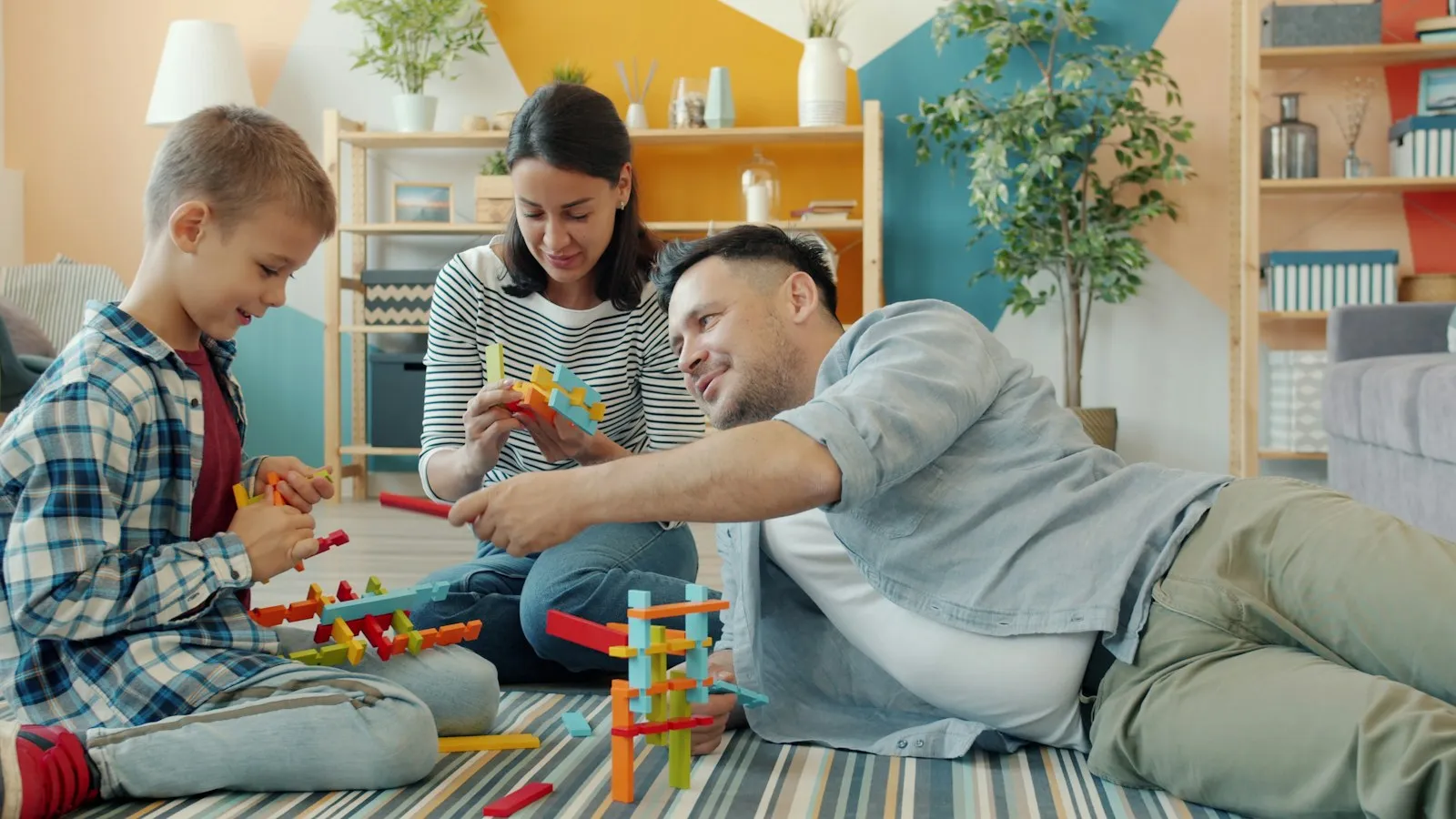 Yerde çocuklarıyla birlikte blok oyunu oynayan anne ve baba